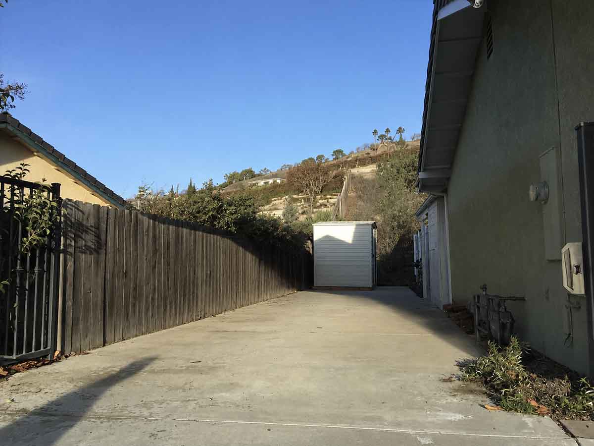 Narrow driveway before a horizontal A-frame carport is installed